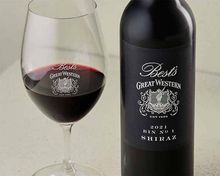 Glass of red wine next to a bottle of Best's Wines Bin No. 1 Shiraz wine.